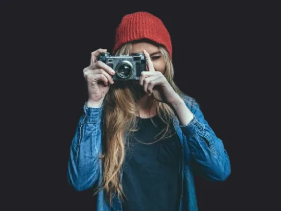 Before: a woman in a red beanie holding a camera, cut out on a black background